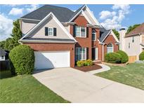 Beautiful two-story brick home featuring a two-car garage, manicured lawn, and traditional architectural details at 566 Vintage Pointe Run, Mableton, GA 30126