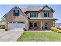 Charming two-story brick home featuring a well-maintained front yard and attached two-car garage at 55 Sudderth St, Buford, GA 30518