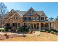 Beautiful two-story brick and stone home with a covered front porch and manicured landscaping at 930 Shepards Ct, Roswell, GA 30075