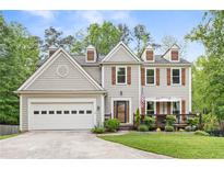 Charming two-story home with a manicured lawn, front porch, and attached garage, perfect for suburban living at 10090 Feather Sound Ct, Alpharetta, GA 30022
