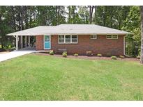 Charming single-story brick home featuring a manicured front lawn and a bright blue front door at 1140 Starline Se Dr, Smyrna, GA 30080