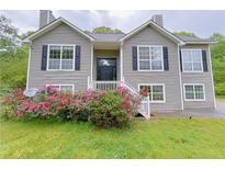 Charming two-story home featuring lush pink rhododendrons, gray siding, and black window shutters at 3342 Windpointe Ct, Buford, GA 30519