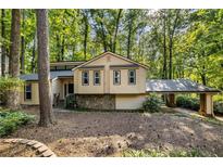 Charming home featuring a stone accent base, siding and covered parking, nestled among mature trees at 203 Concorde Sw Way, Lilburn, GA 30047