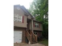 Two story home with tan siding, brick facade, red shutters, and wooden staircase at 143 Delane Dr, Dallas, GA 30157