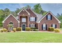 Stunning brick home boasts meticulous landscaping, a manicured lawn, and an inviting entryway at 2417 Saint Feagin Pl, Powder Springs, GA 30127