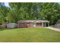 Charming brick home with a well-manicured lawn, convenient carport, and storage shed at 4781 Lincoln Ne Dr, Kennesaw, GA 30144