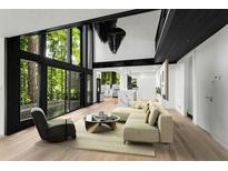 Bright living room featuring a modern sofa, accent chair, and large windows offering scenic views of surrounding trees at 5020 Vallo Vista Ct, Atlanta, GA 30342