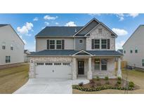 Charming two-story home featuring a brick and siding exterior, covered porch, and two-car garage at 553 Princeton Elm Place Way, Lawrenceville, GA 30045