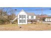 Two-story home with black shutters, front porch, and a detached wooden staircase at 700 W College St, Bowdon, GA 30108