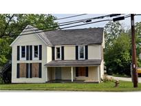 An exterior view of a two-story home with light yellow siding and black shutters at 700 W College St, Bowdon, GA 30108