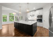 Bright kitchen featuring a large island with a white countertop and pendant lighting at 4294 Silver Peak Pkwy, Suwanee, GA 30024