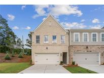 Charming townhome with a two-car garage, brick facade, and well-manicured lawn on a sunny day at 4651 Larkfield Way, Powder Springs, GA 30127