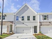 Charming townhome featuring a painted brick facade, attached garage, and manicured landscaping at 4651 Larkfield Way, Powder Springs, GA 30127