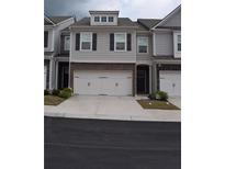 Charming townhome with a two-car garage, gray siding, and classic black shutters at 7624 Squire Ct, Fairburn, GA 30213