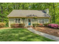 Charming one-story home features a lush green lawn, mature landscaping, and a welcoming walkway to the front door at 3957 Woodland Cir, Conyers, GA 30013