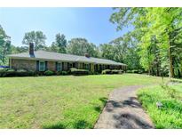 Charming brick ranch-style home with a sprawling lawn and mature trees offering a tranquil and inviting curb appeal at 168 Woodland Valley Rd, Lawrenceville, GA 30046