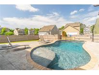 Backyard swimming pool and stone patio with lounge chairs and privacy fence on a sunny day at 408 Blue Sky Cir, Acworth, GA 30102