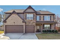 Charming two-story brick home boasts a two-car garage and a well-maintained front lawn at 3373 Shoals Ridge Dr, Dacula, GA 30019
