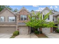 Charming townhome with brick accents, a well-maintained lawn, and an attached single-car garage at 7168 Kingswood Run Dr, Atlanta, GA 30340