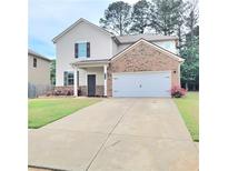 Charming two-story home with a brick and vinyl facade, an attached two car garage, and a well-manicured front lawn at 110 Halibut Cir, Covington, GA 30016