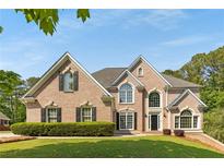 Charming brick home featuring manicured lawn, dormer windows, arched windows, and a well-kept landscape at 679 Gold Valley Pass, Canton, GA 30114