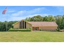 Spacious ranch-style home with manicured lawn, lush landscaping, and an American flag waving in front at 1724 Arbor Hill Rd, Canton, GA 30115