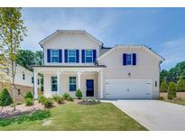 Charming two-story home with a well-manicured lawn, blue shutters, covered porch, and attached garage at 3311 Burkston Pl, Buford, GA 30519