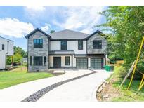 Two-story home featuring a modern design, gray and white facade, and a concrete driveway with a landscaped center strip at 2740 Drew Valley Ne Rd, Brookhaven, GA 30319