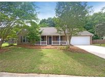 Charming single-story home with a brick facade, manicured lawn and attached two-car garage and front porch at 2012 Elm Grove Ln, Hampton, GA 30228