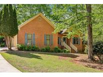 Charming brick home featuring a well-manicured lawn, complemented by lush greenery and a welcoming entrance with steps at 318 Dogwood Trce, Mcdonough, GA 30252