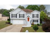 Charming two-story home featuring an attached garage, neatly landscaped yard and a bright orange front door at 440 Hickory Glen Sw Ln, Atlanta, GA 30311