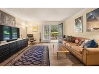 Cozy living room with a brown leather couch, wooden coffee table, and sliding glass doors to the outdoor patio at 3472 Essex Ave # 81, Atlanta, GA 30339
