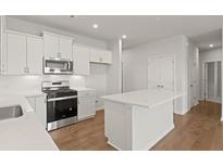 Well-lit kitchen features white cabinets, stainless appliances, and a central island with a white countertop at 488 Village Ln, Fairburn, GA 30213