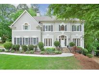 Beautiful two-story home with a manicured front yard, lush landscaping, and charming architectural details at 9900 Hunt Club Way, Johns Creek, GA 30022