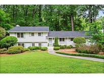 Charming white home with lush green lawn and mature trees providing a serene and inviting curb appeal at 1518 Rochelle Dr, Atlanta, GA 30338