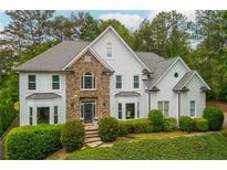 Stunning two-story home with a stone facade, arched window, lush landscaping, and an inviting entrance at 725 Eider Down Ct, Alpharetta, GA 30022