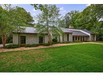 Charming single-story home with stone facade, metal roof and lush green lawn at 5120 Jett Forest Trl, Atlanta, GA 30327