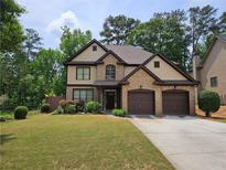Charming two-story home with a well-manicured lawn and a two-car garage, complemented by lush landscaping at 3943 Dunaire Dr, Stone Mountain, GA 30083
