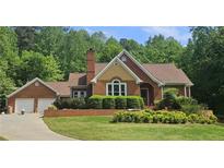 Charming brick home with a manicured lawn, mature trees, and a two-car garage at 1124 Bend Creek Trl, Suwanee, GA 30024
