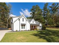 Stunning two-story white home with a lush green lawn and beautiful landscaping, and black trim around the windows at 9770 Coleman Rd, Roswell, GA 30075
