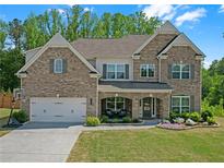 Charming brick two-story home featuring a well-manicured lawn, covered entryway, and attached two-car garage at 319 Parkside Meadow Dr, Marietta, GA 30064