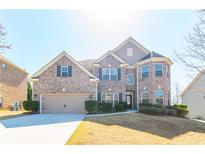 Charming brick home featuring a well-manicured lawn, attached two-car garage, and mature landscaping at 335 Roberts Run Cv, Suwanee, GA 30024