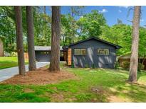 Charming exterior of a updated home with a dark facade, complemented by lush landscaping and mature trees at 3964 Gretna Green Dr, Decatur, GA 30035
