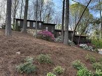 Charming brown home with stone base and colorful flower landscaping on a wooded lot at 475 Nottingham Dr, Marietta, GA 30066