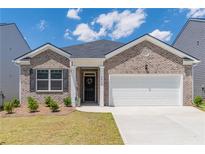 Charming brick home featuring a two-car garage, well-maintained lawn, and inviting entrance at 2010 Vidalia Ct, Dacula, GA 30019