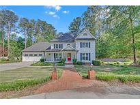 Charming two-story home with a manicured front lawn, red door, and a welcoming front porch at 4985 Miller Sw Rd, Lilburn, GA 30047