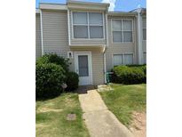 Tan siding townhouse with a well-manicured lawn and clean walkway leading to the front door at 102 Governors Dr, Forest Park, GA 30297