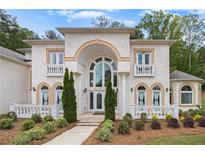 Stunning two-story brick home features a large arched entryway, lush landscaping, and decorative balustrades at 2425 Wild Oak Ct, Stockbridge, GA 30281