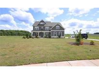 Two-story home featuring gray siding, a covered porch, and large front yard at 125 Leveret Rd, Locust Grove, GA 30248