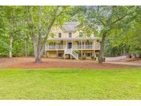 Charming yellow two-story home with a spacious front porch and well-manicured lawn surrounded by mature trees at 115 Eagle Ridge Dr, Canton, GA 30114